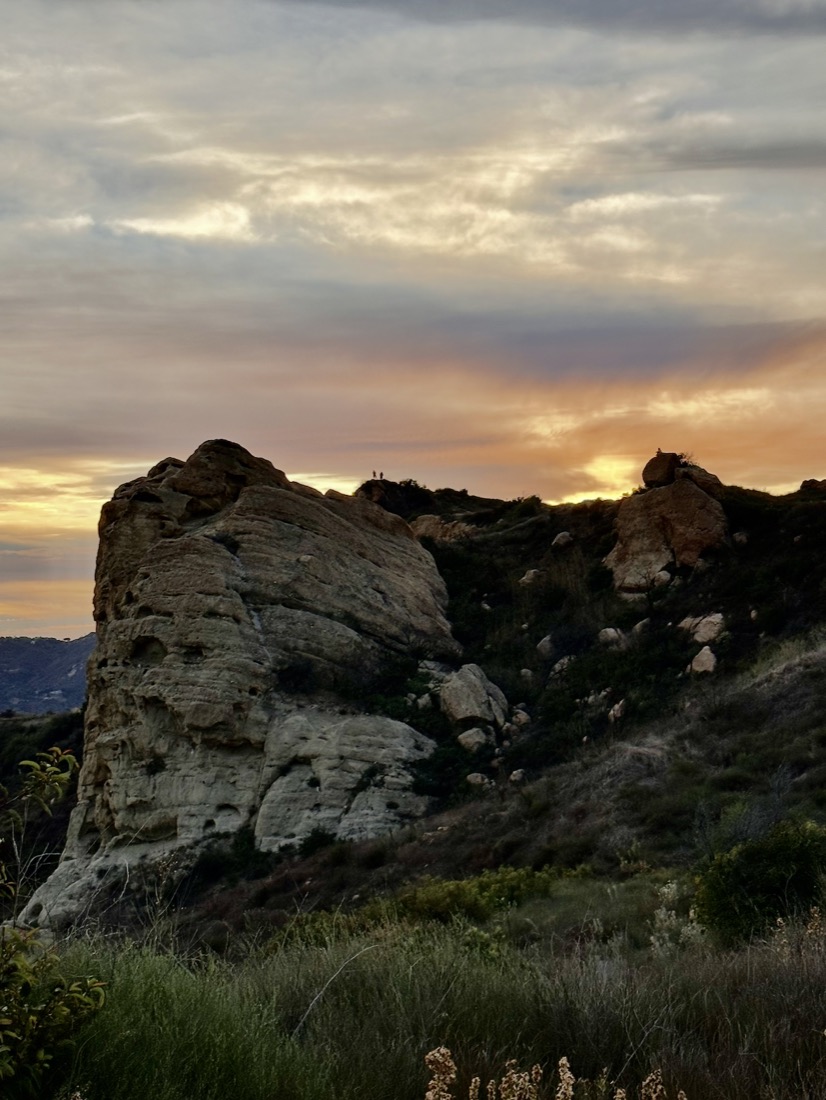 A sandstone rock formation against an orange sunset
