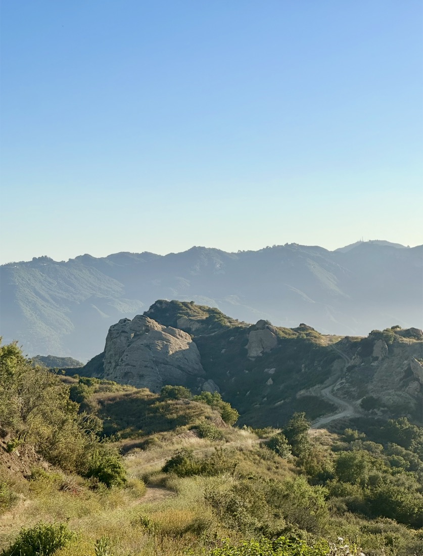 Hazy mountain ridges with a dirt trail winding through them
