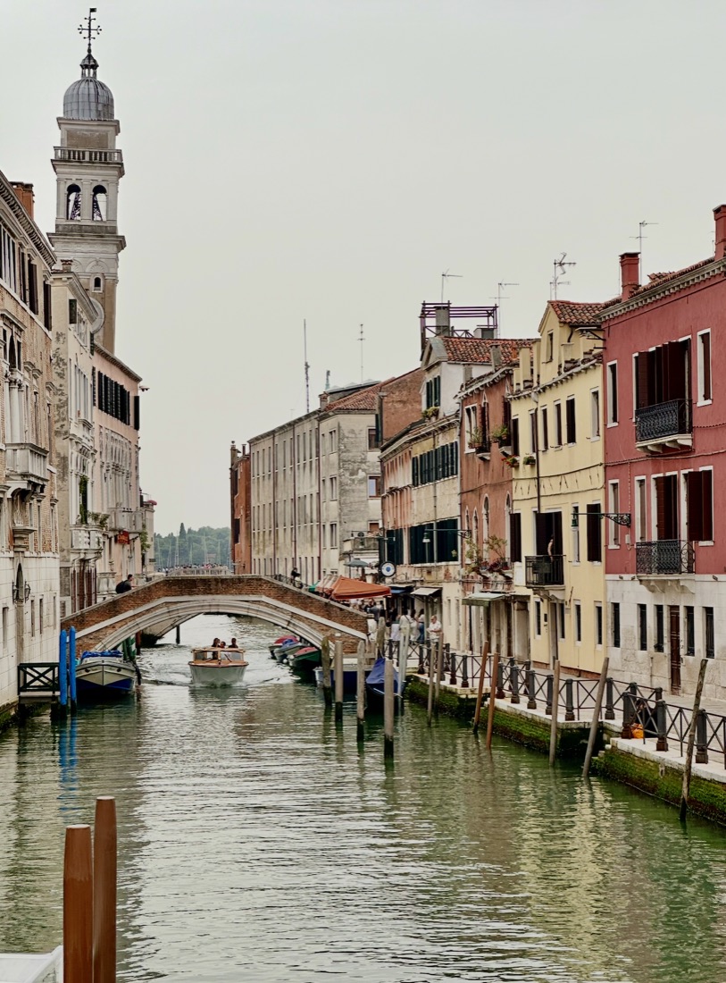 A canal in Venice with a boat passing under a bridge