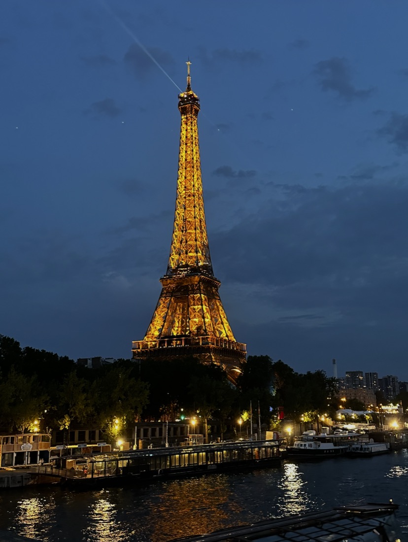 The Eiffel Tower lit up at night above the Seine